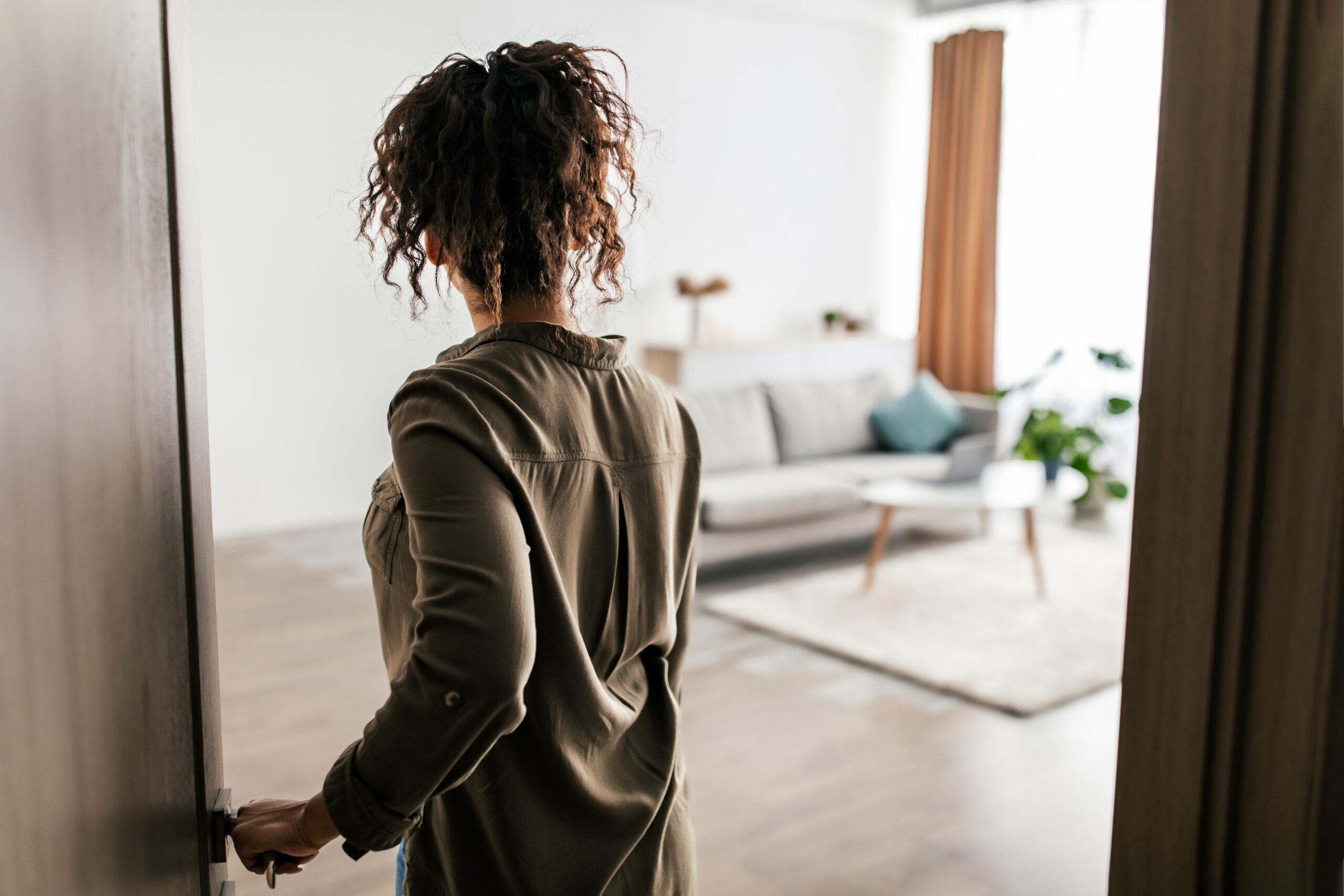 Back View African American Lady Opening Door Entering Apartment - Vivenzia Home Sevilla